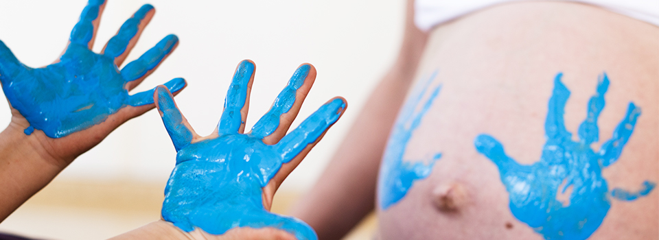 Themenbild - Schwangerschaftsbauch mit farbigen Kinderhandabdrücken