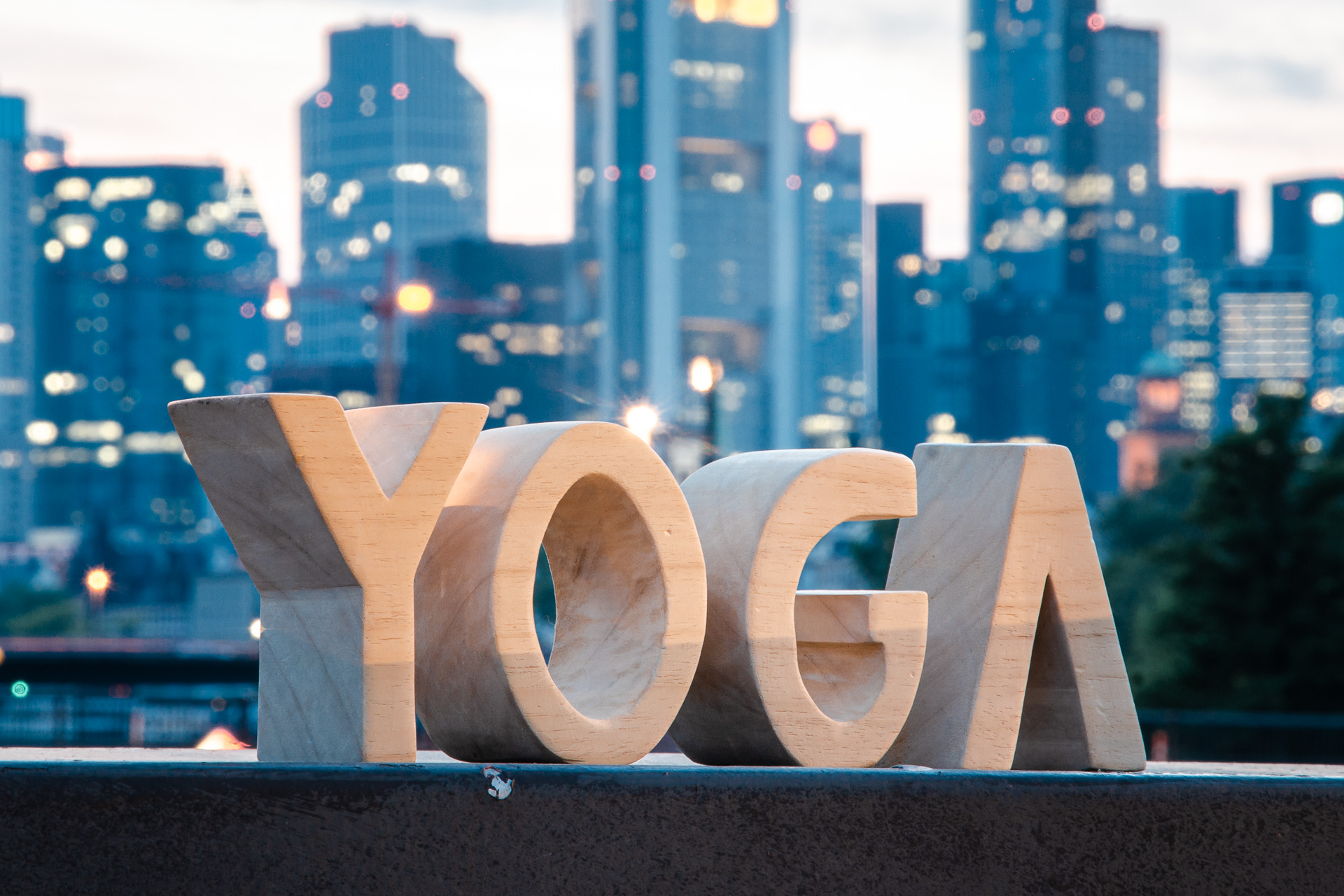Yoga-Schriftzug aus geschnitzten Holzbuchstaben vor der Skyline Von Frankfurt am Main